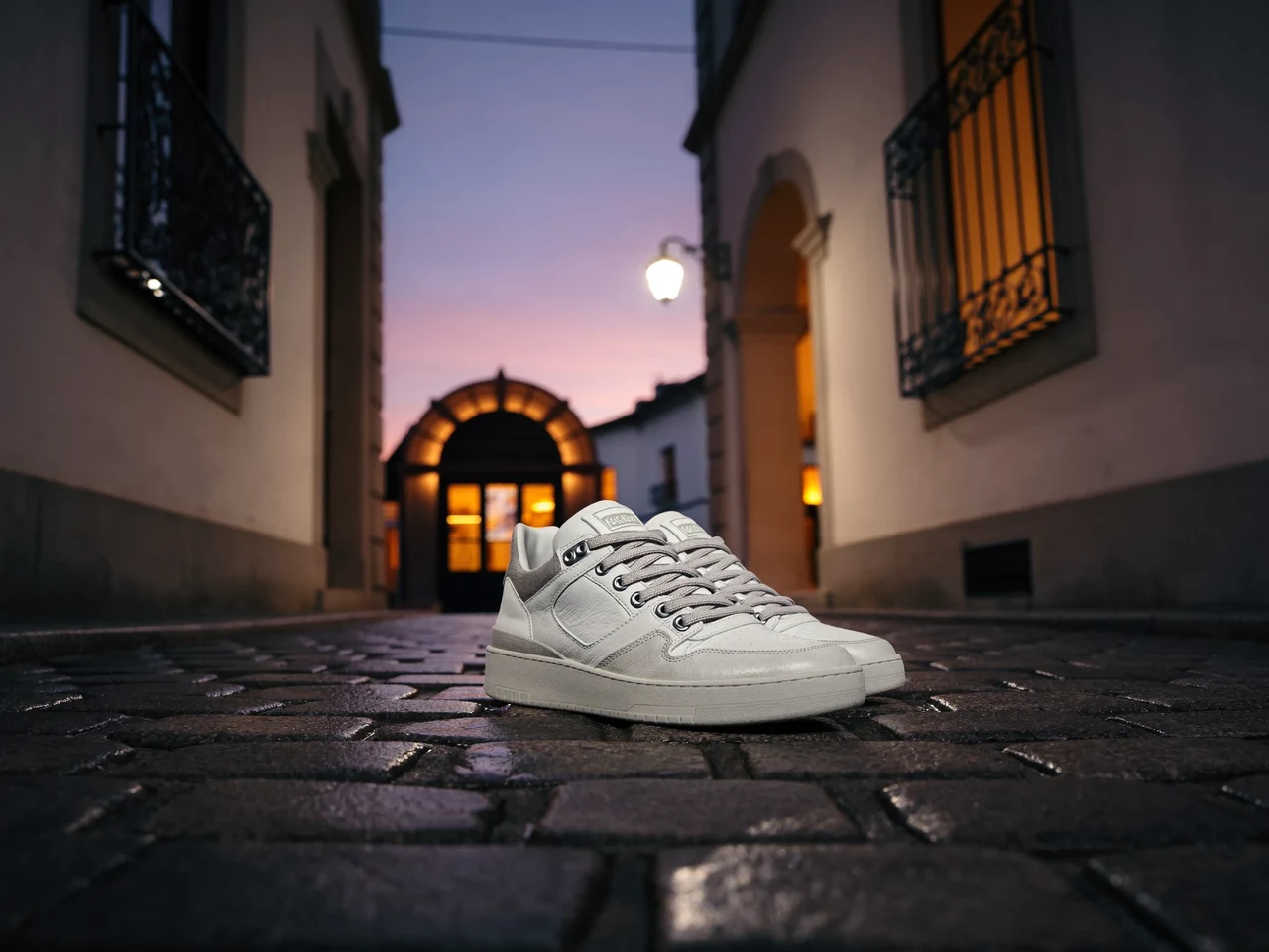 Sneaker auf nassem Kopfsteinpflaster einer Schweizer Altstadt im Abendlicht, illustrativ dargestellt