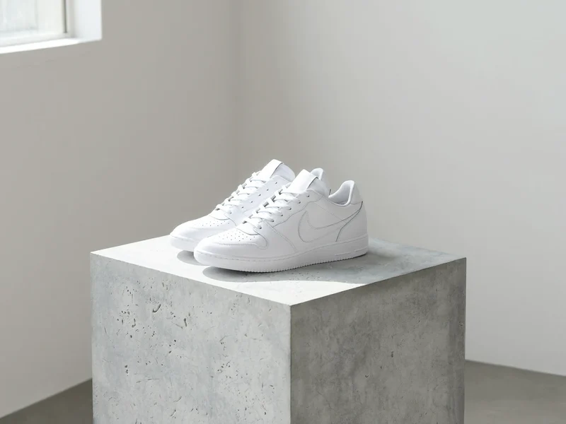 Weisser Leder-Low-Top auf heller Betonfläche im ruhigen Studiolicht