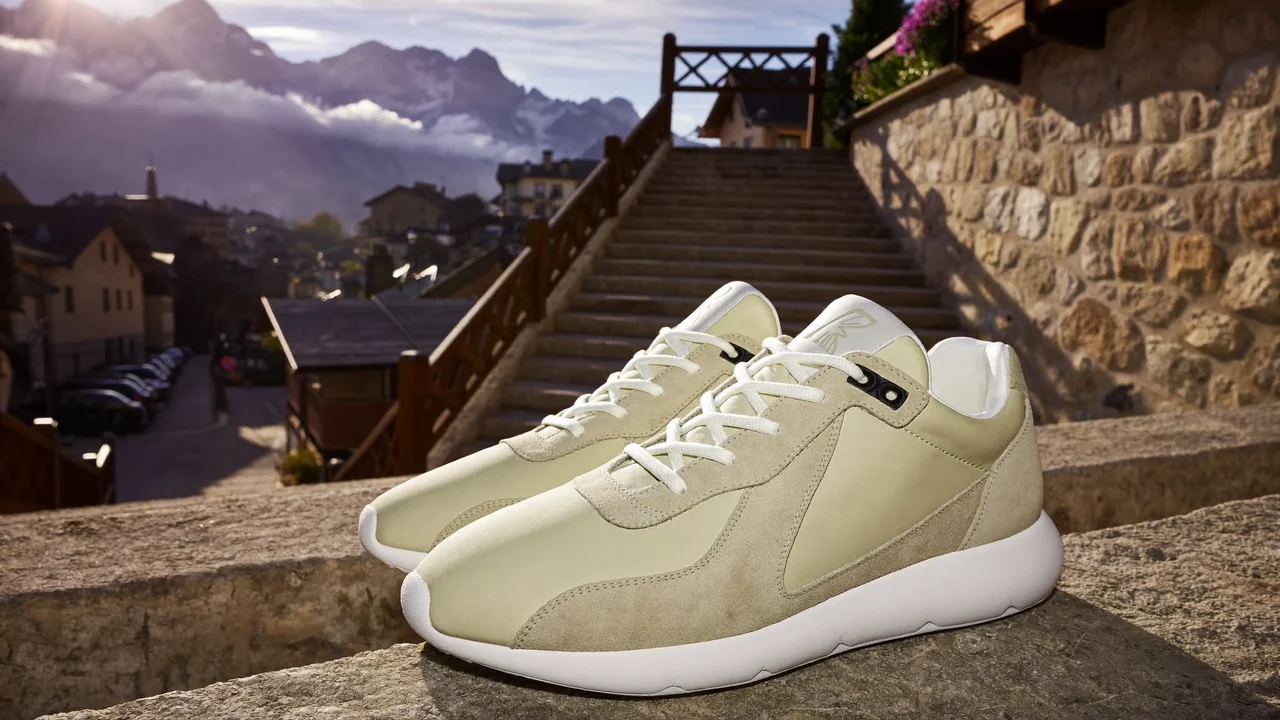 Sneaker auf einer Treppe in einer Alpenstadt, im Hintergrund weiche Berge