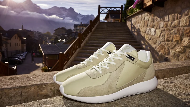 Sneaker auf einer Treppe in einer Alpenstadt, im Hintergrund weiche Berge